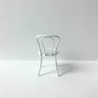 Wit metalen stoeltje voor het poppenhuis