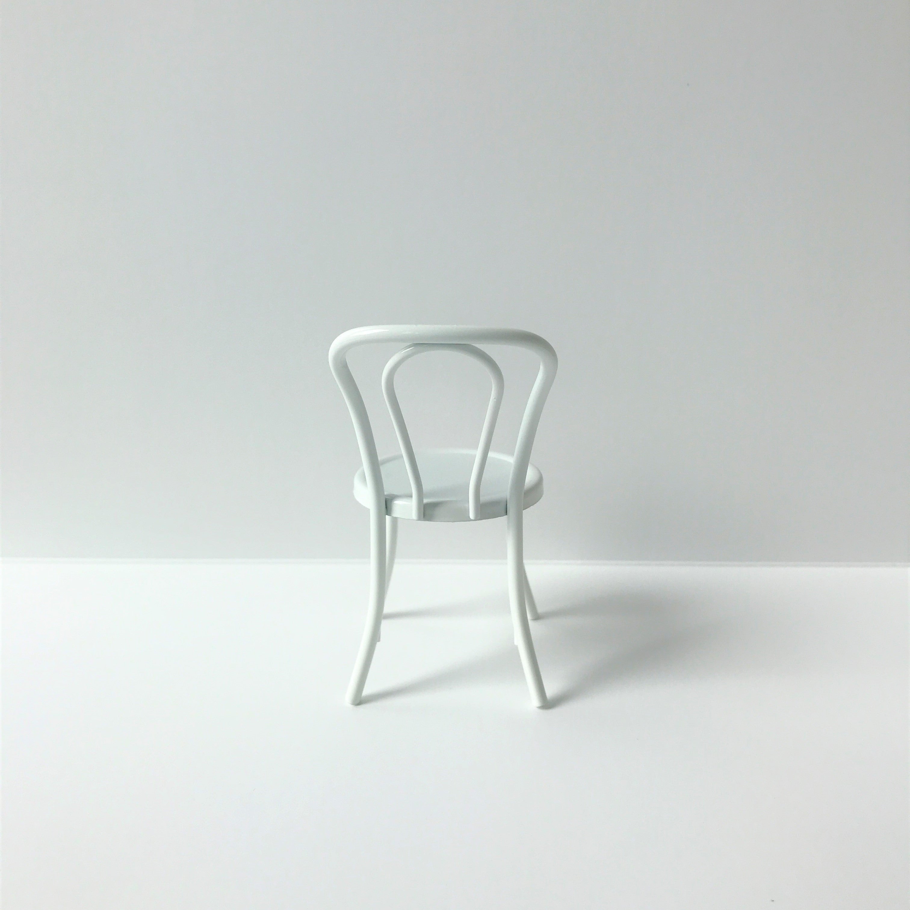 Wit metalen stoeltje voor het poppenhuis