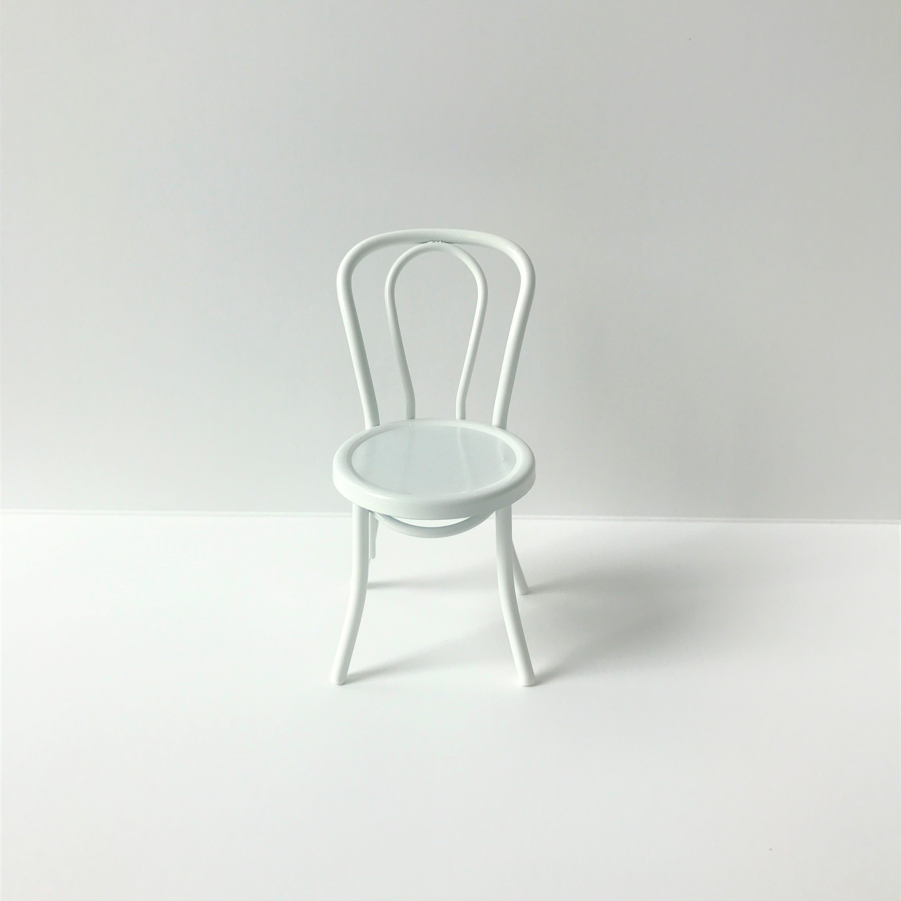 Wit metalen stoeltje voor het poppenhuis