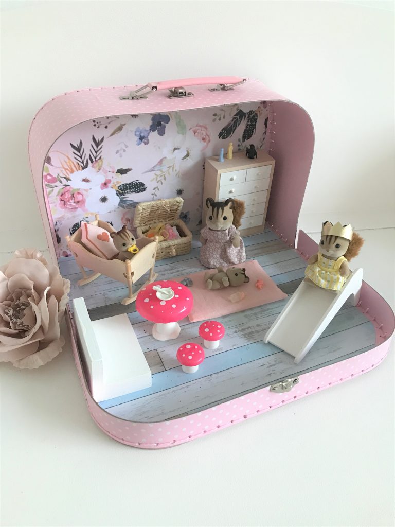 A travel dollhouse suitcase with furniture and a squirrel family.